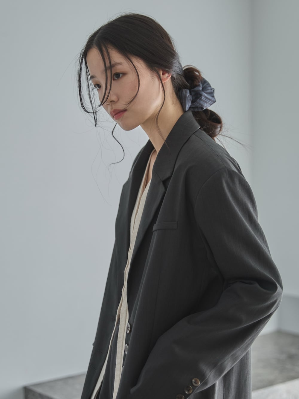 グレー系のテーラードジャケット、ホワイト系のカーディガン/ボレロ、グレー系のスラックスを着用したレディースの冬コーディネートの4枚目の写真