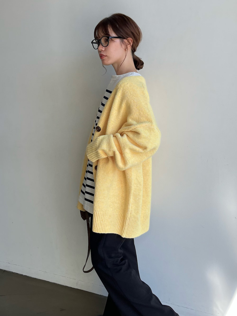 ホワイト系のTシャツ/カットソー、イエロー系のカーディガン/ボレロ、ブラック系のスラックスを着用したレディースの秋コーディネートの4枚目の写真