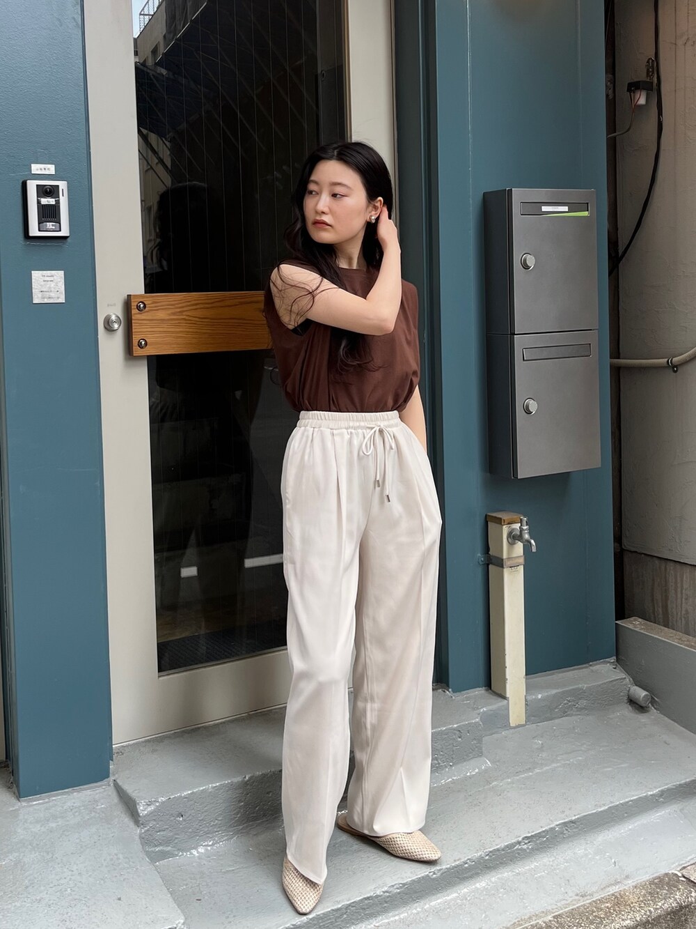 ブルー系のニット/セーター、ブラック系のスラックス、ホワイト系のスラックスを着用したレディースの春コーディネートの2枚目の写真