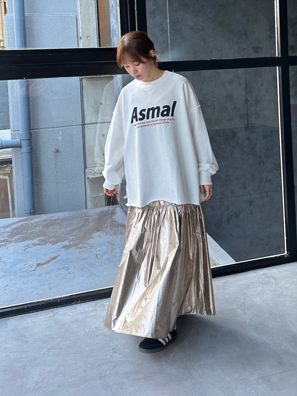 ブラック系のスニーカー、ホワイト系のスウェット、ゴールド系のスカートを着用したレディースの冬コーディネートの2枚目の写真