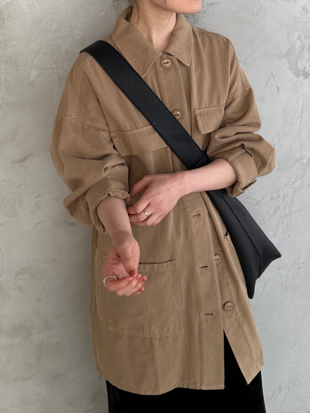 ブラック系のショルダーバッグ、ブラック系のスカート、ベージュ系のミリタリージャケットを着用したレディースの春コーディネートの3枚目の写真