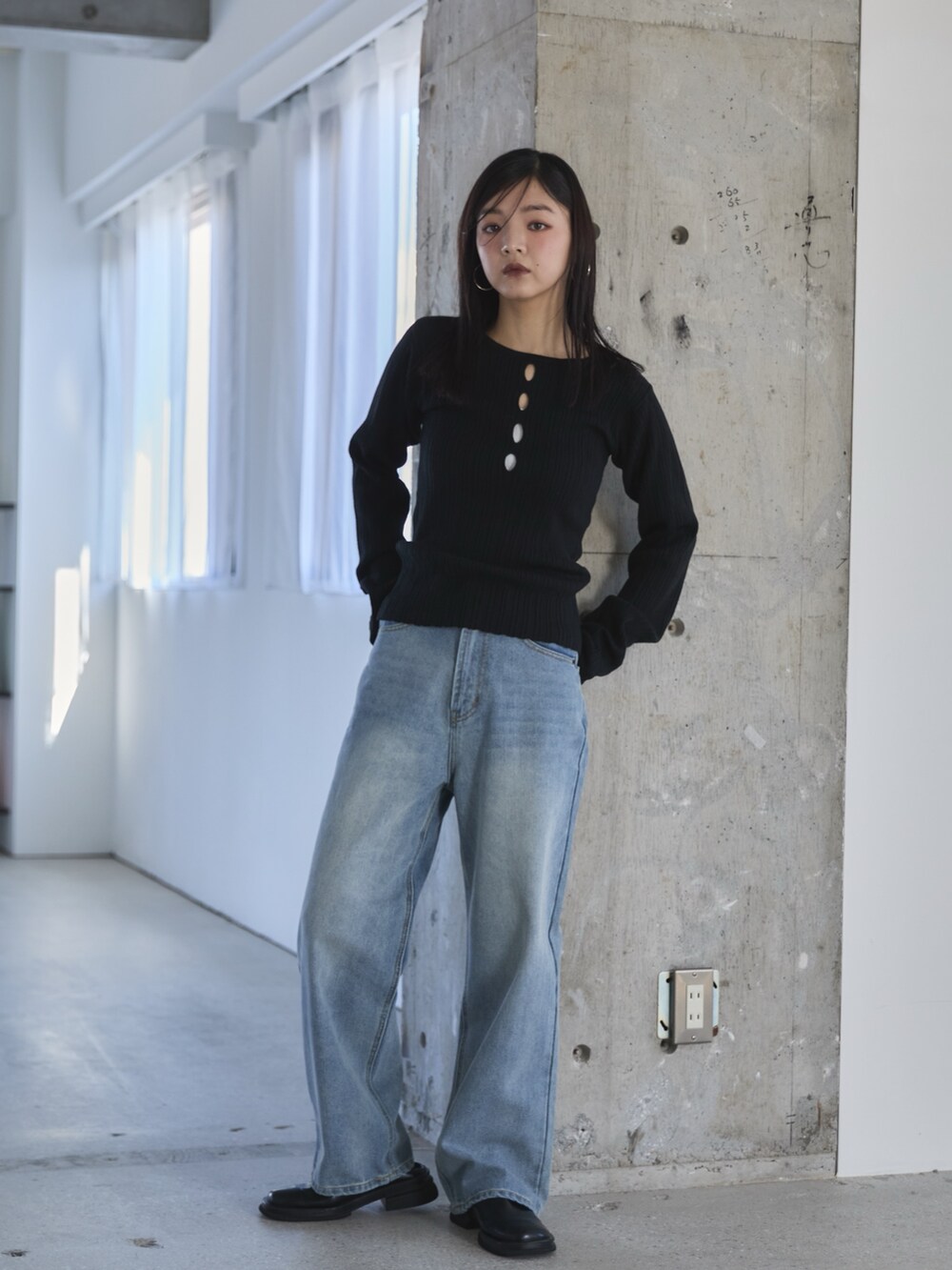 ブラック系のニット/セーター、ブラック系のスリッポン、ブルー系のデニムパンツを着用したレディースの冬コーディネートの2枚目の写真
