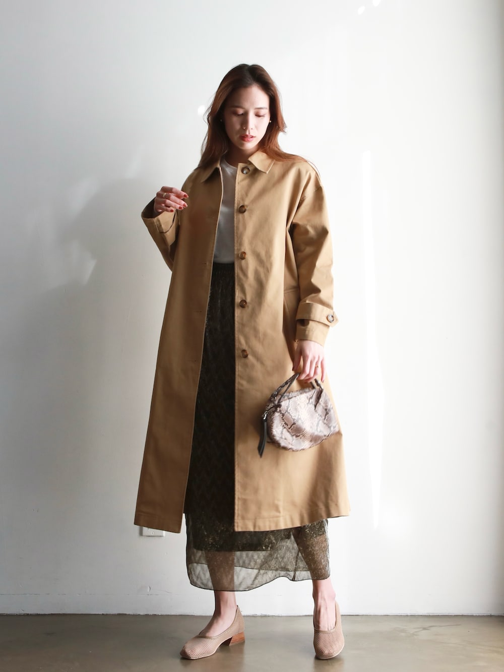 ブラック系のハンドバッグ、ベージュ系のステンカラーコート、ブラック系のシャツ/ブラウスを着用したレディースの冬コーディネートの2枚目の写真