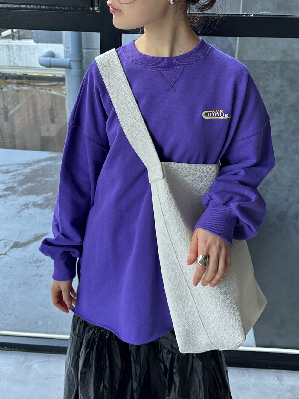 パープル系のスウェット、ブラック系のショルダーバッグ、ブラック系のスカートを着用したレディースの冬コーディネートの5枚目の写真