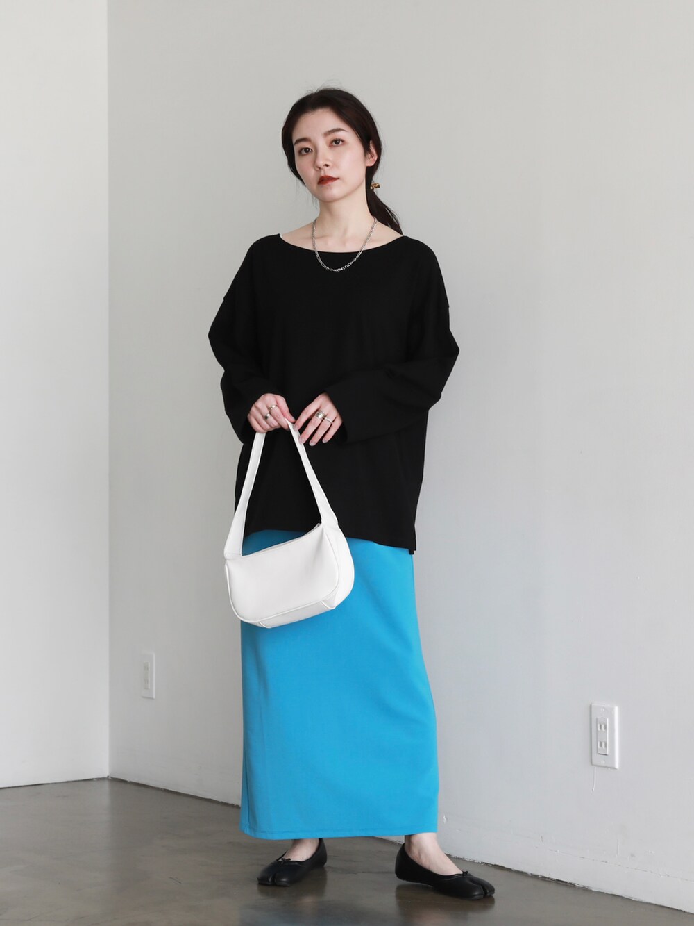 ブラック系のパンプス、ブルー系のスカート、ホワイト系のハンドバッグを着用したレディースの夏コーディネートの2枚目の写真