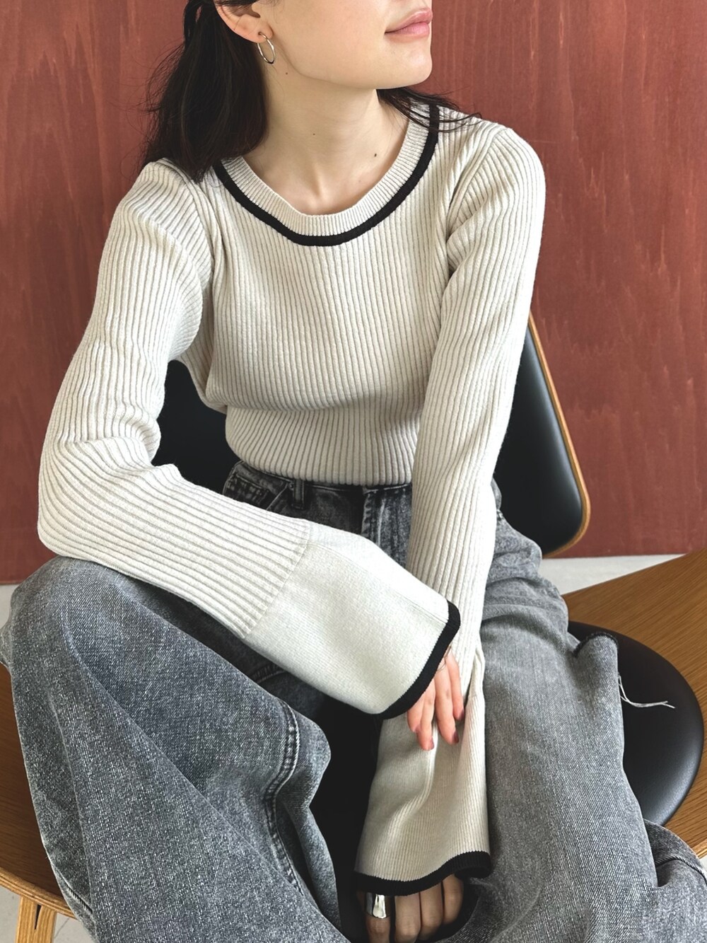 ブラック系のデニムパンツ、ブラック系のスリッポン、ホワイト系のニット/セーターを着用したレディースの秋コーディネートの5枚目の写真