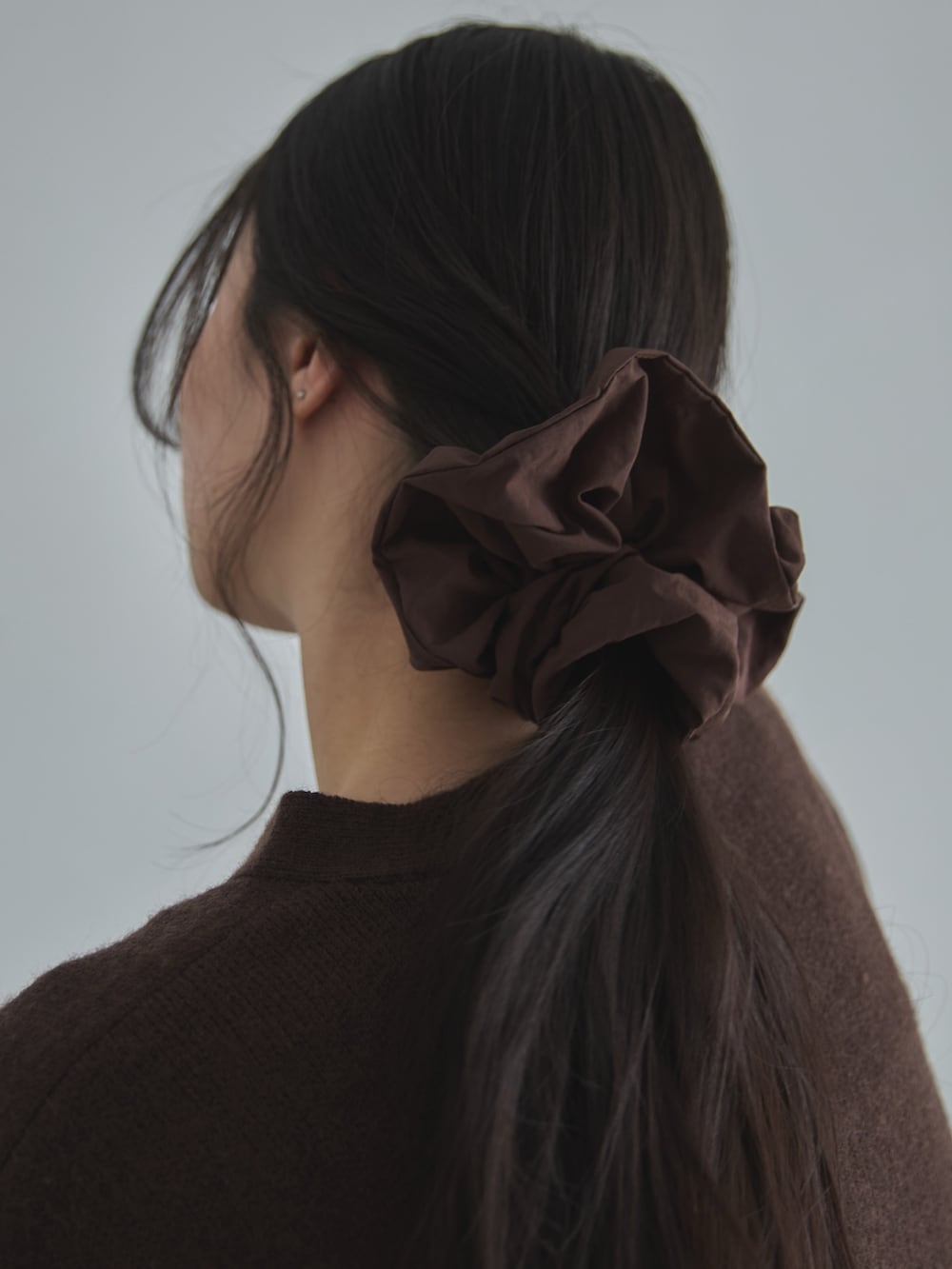 ブラウン系のカーディガン/ボレロ、ブラウン系のその他パンツ、ブラウン系のシュシュを着用したレディースの冬コーディネートの2枚目の写真