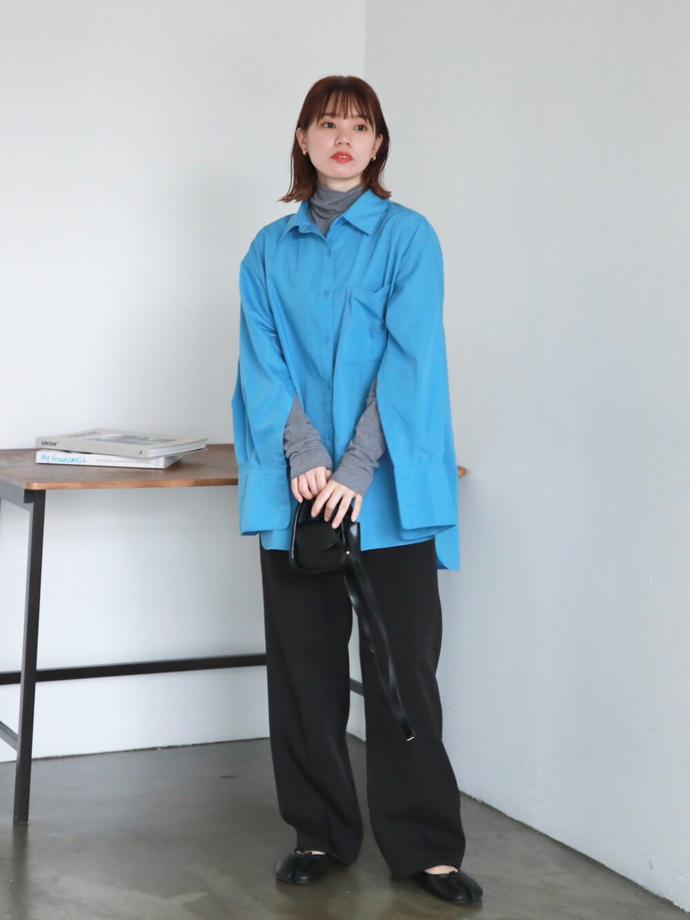 ブラック系のスラックス、ブラック系のパンプス、ブルー系のシャツ/ブラウスを着用したレディースの秋コーディネートの2枚目の写真