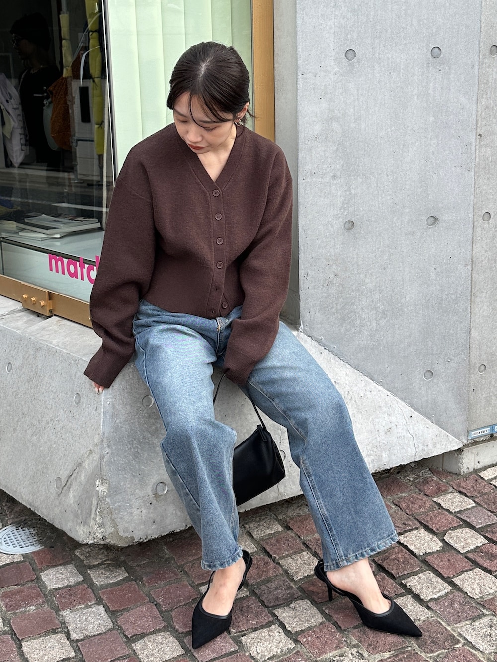 ブラウン系のカーディガン/ボレロ、ブルー系のデニムパンツ、ブラック系のショルダーバッグを着用したレディースの冬コーディネートの5枚目の写真