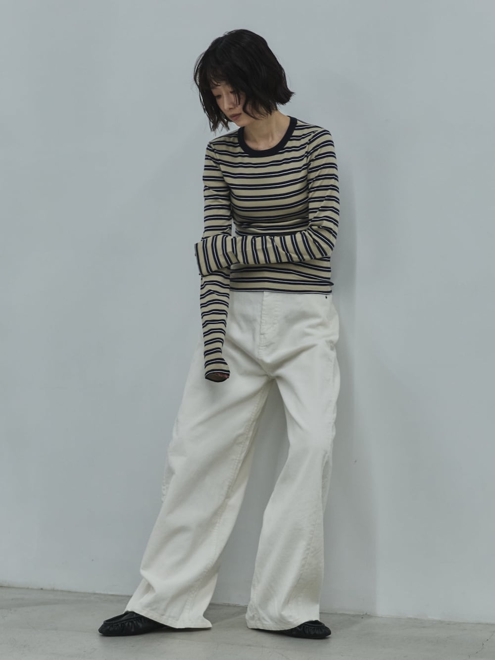 ベージュ系のTシャツ/カットソー、ホワイト系のデニムパンツ、ブラック系のローファーを着用したレディースの秋コーディネートの2枚目の写真