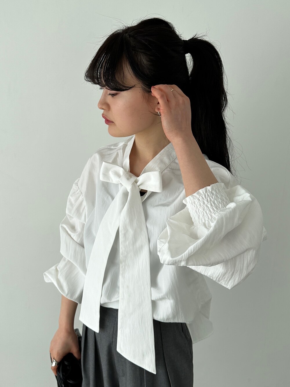 ホワイト系のシャツ/ブラウス、グレー系のスラックス、ブラック系のショルダーバッグを着用したレディースの冬コーディネートの4枚目の写真