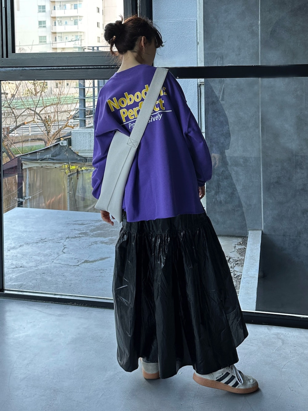 パープル系のスウェット、ブラック系のショルダーバッグ、ブラック系のスカートを着用したレディースの冬コーディネートの4枚目の写真