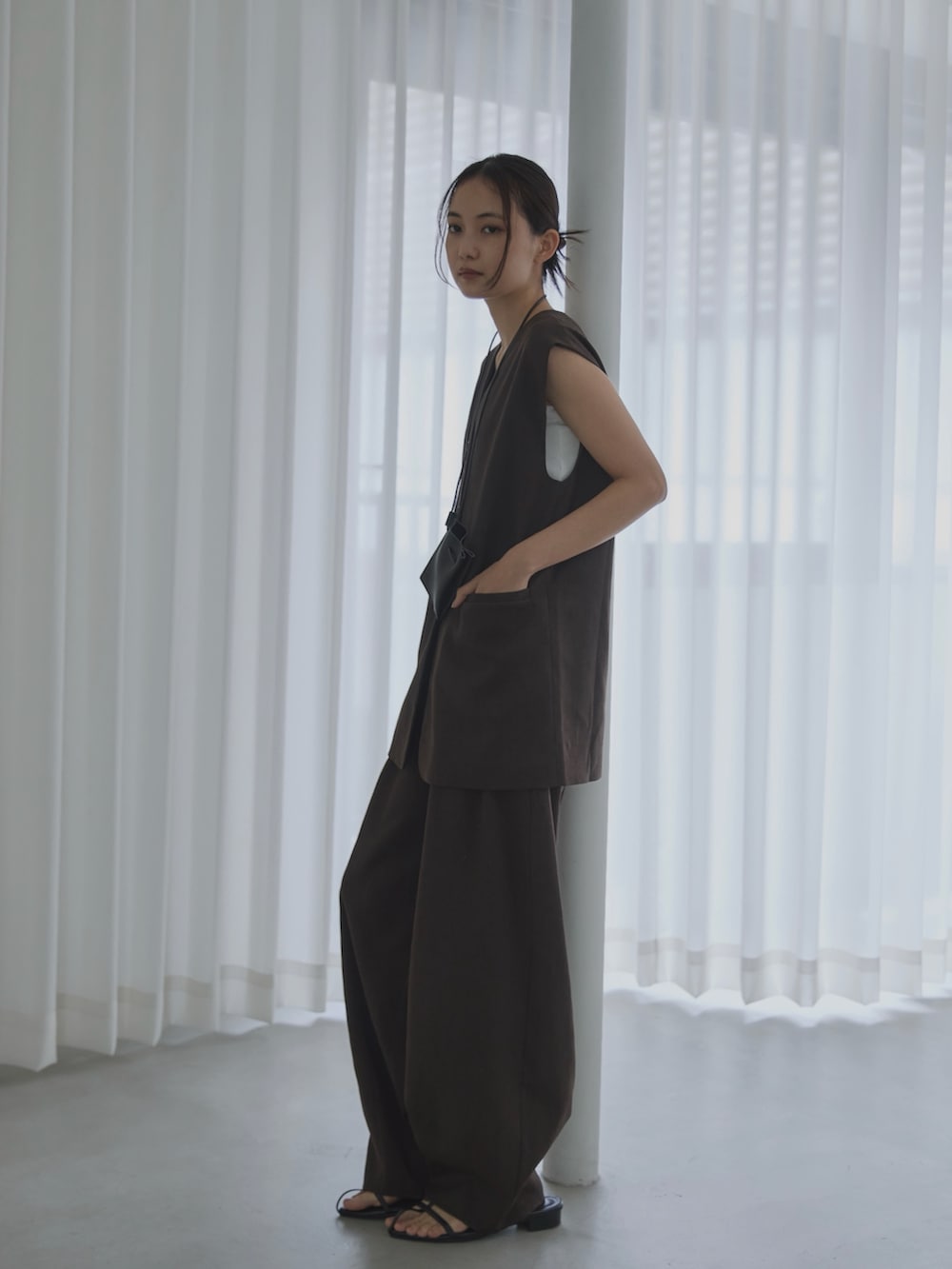 ブラウン系のベスト、ブラウン系のスラックス、ブラック系のサンダルを着用したレディースの夏コーディネートの2枚目の写真