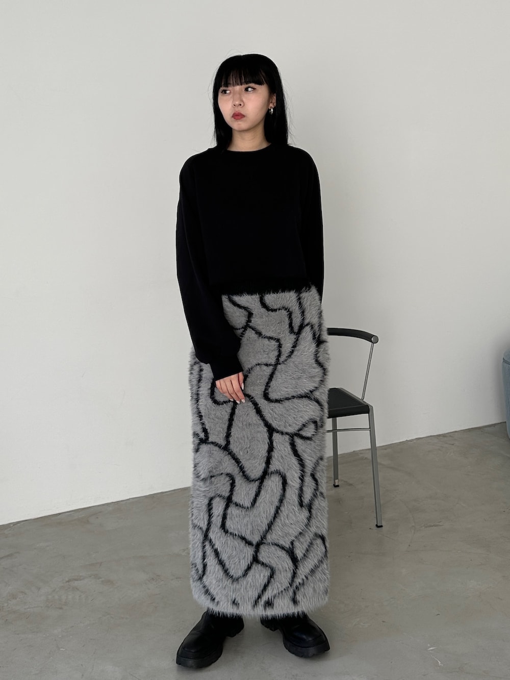 グレー系のスカート、ブラック系のブーツ、ブラック系のスウェットを着用したレディースの冬コーディネートの2枚目の写真