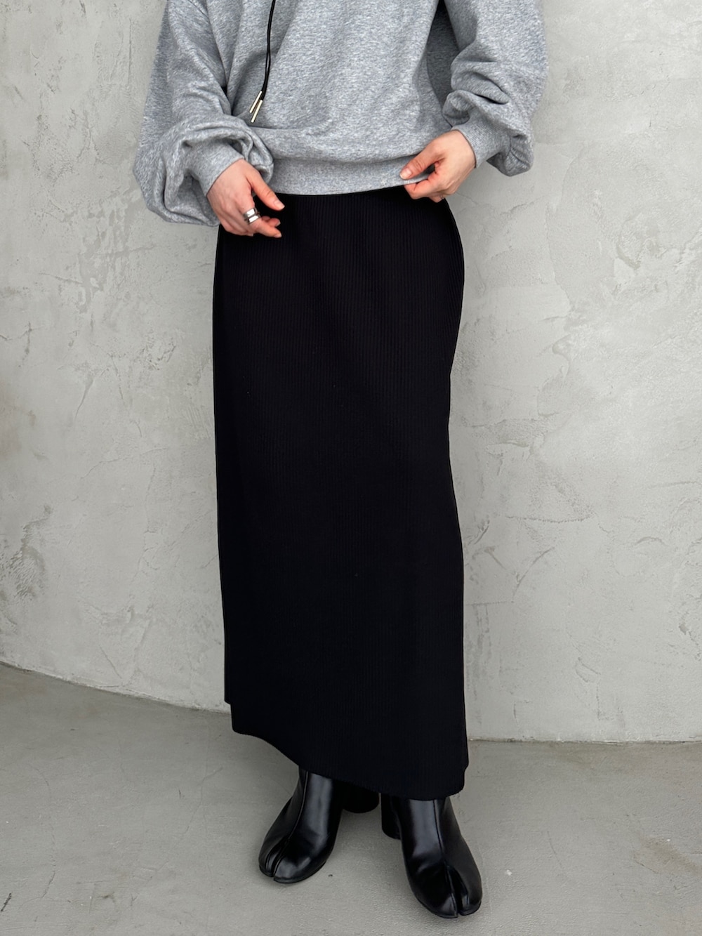 グレー系のスウェット、ブラック系のスカート、ブラック系のブーツを着用したレディースの秋コーディネートの2枚目の写真