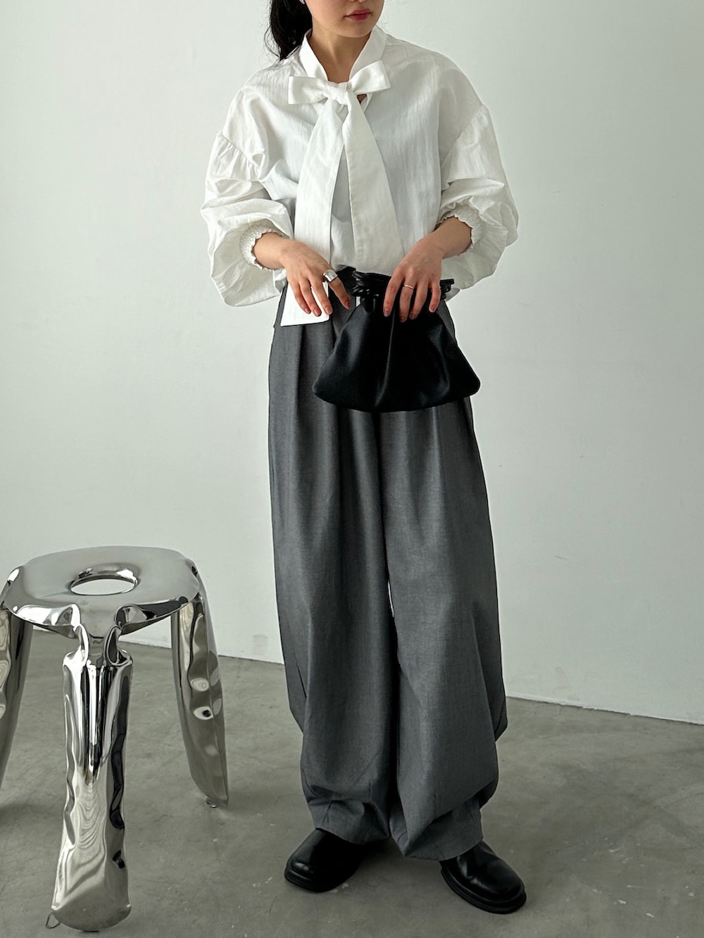 ホワイト系のシャツ/ブラウス、グレー系のスラックス、ブラック系のショルダーバッグを着用したレディースの冬コーディネートの3枚目の写真