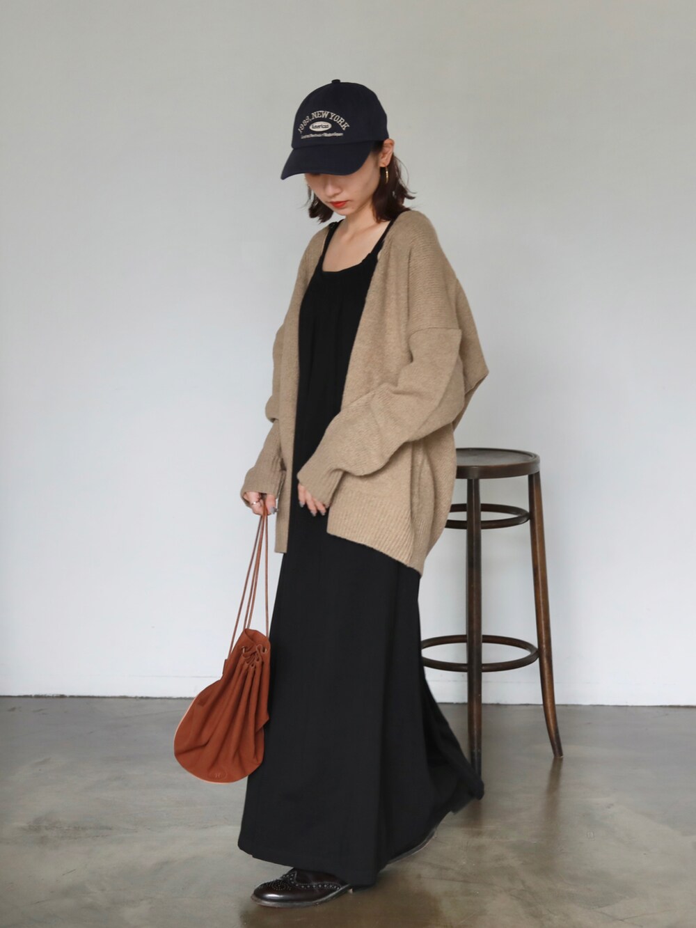 ブラック系のワンピース、ベージュ系のカーディガン/ボレロ、ブルー系のキャップを着用したレディースの夏コーディネートの2枚目の写真