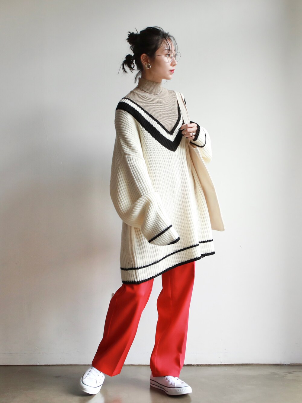 ブラック系のニット/セーター、ホワイト系のシャツ/ブラウス、ブラウン系のハンドバッグを着用したレディースの冬コーディネートの3枚目の写真