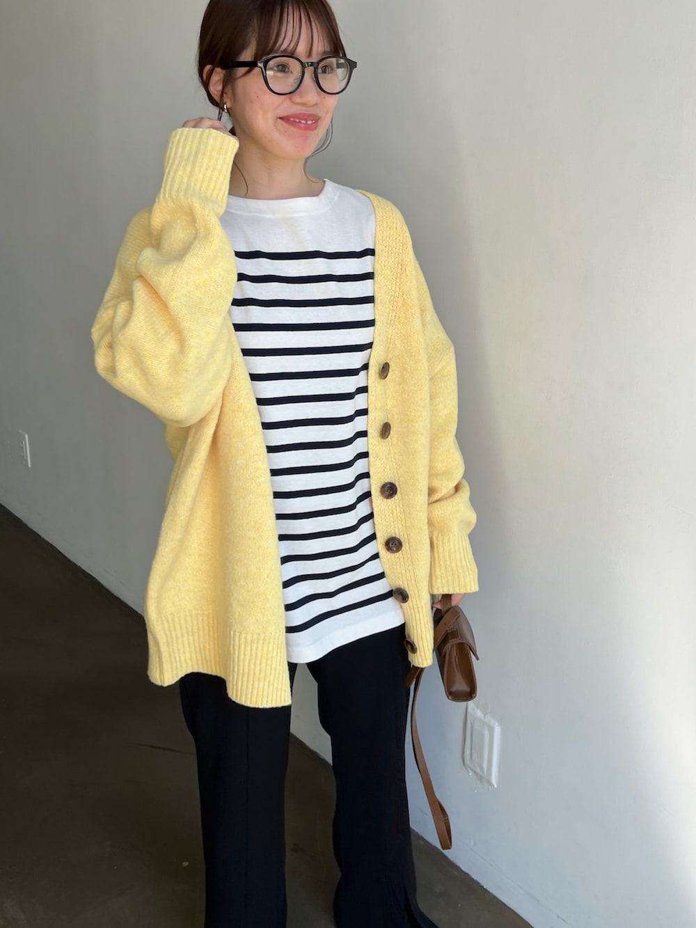 ホワイト系のTシャツ/カットソー、イエロー系のカーディガン/ボレロ、ブラック系のスラックスを着用したレディースの秋コーディネートの2枚目の写真