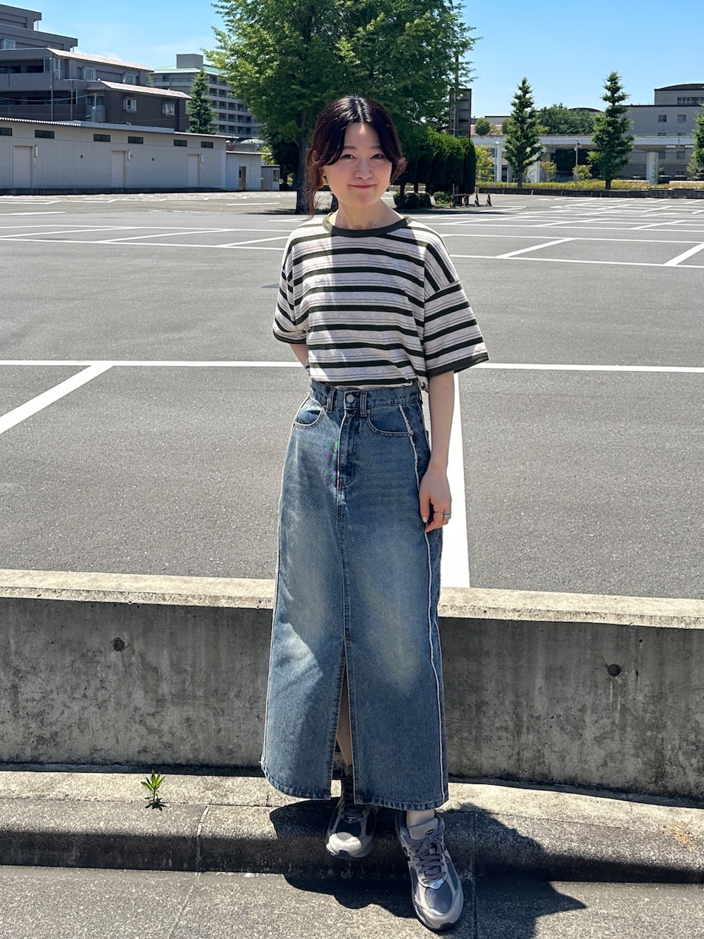 ブルー系のデニムスカート、グリーン系のTシャツ/カットソー、グレー系のスニーカーを着用したレディースの夏コーディネートの3枚目の写真