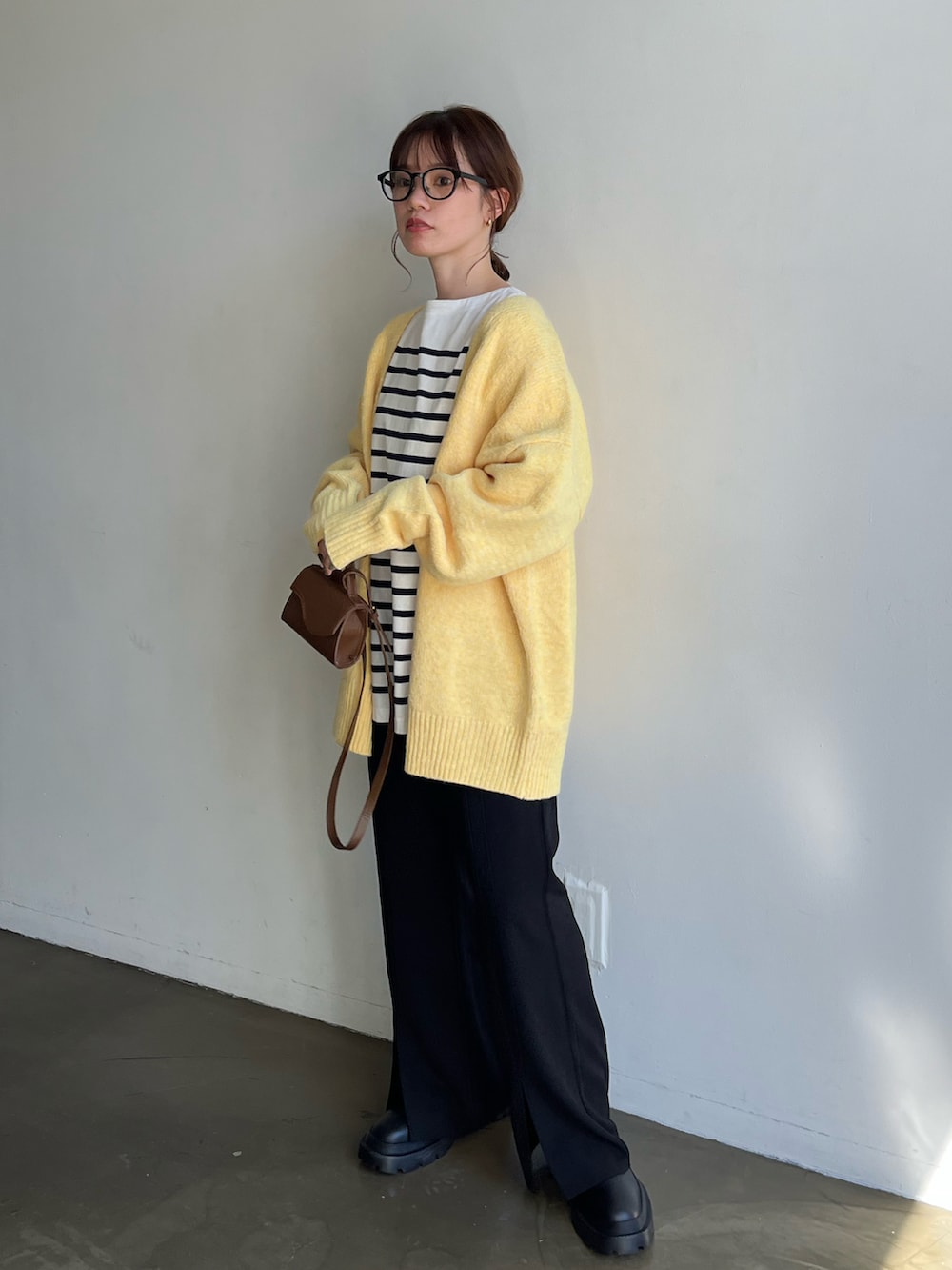 ホワイト系のTシャツ/カットソー、イエロー系のカーディガン/ボレロ、ブラック系のスラックスを着用したレディースの秋コーディネートの3枚目の写真