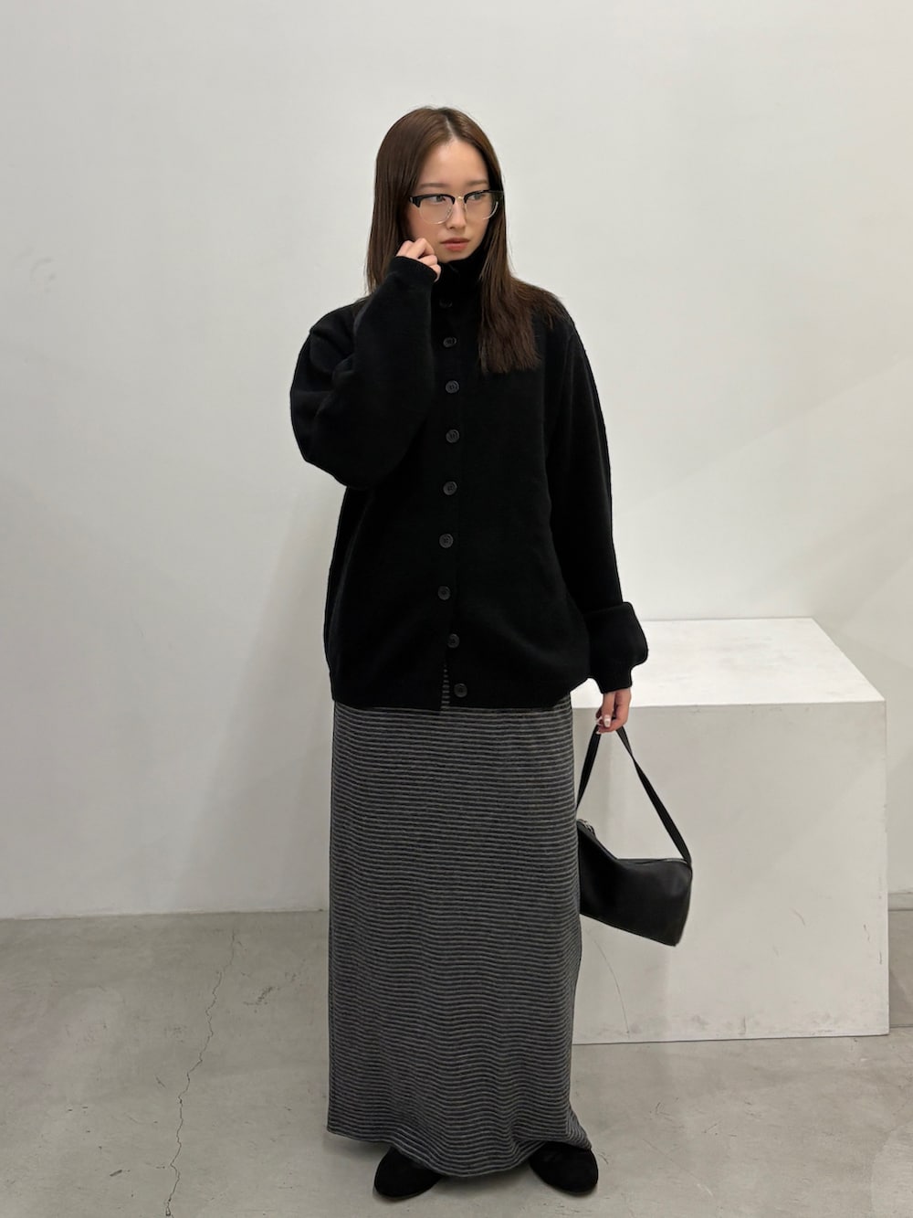 ブラック系のニット/セーター、グレー系のスカート、ブラック系のショルダーバッグを着用したレディースの秋コーディネートの2枚目の写真