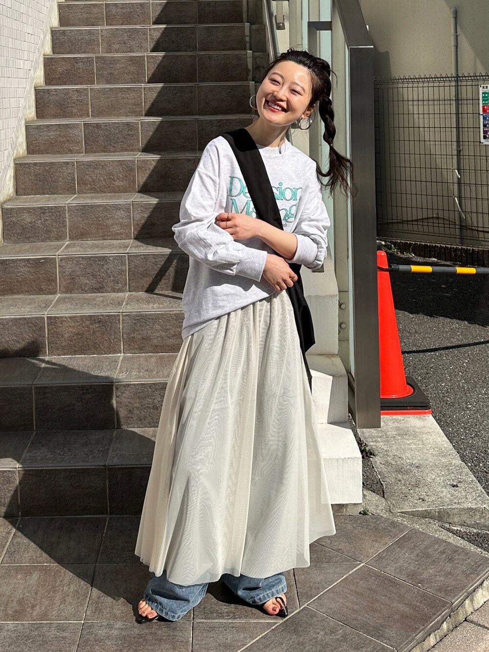 ベージュ系のスウェット、ホワイト系のスカート、ブルー系のデニムパンツを着用したレディースの春コーディネートの2枚目の写真