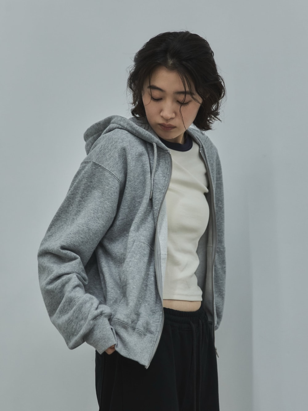 グレー系のパーカー、ホワイト系のTシャツ/カットソー、ブラック系のデニムパンツを着用したレディースの秋コーディネートの2枚目の写真