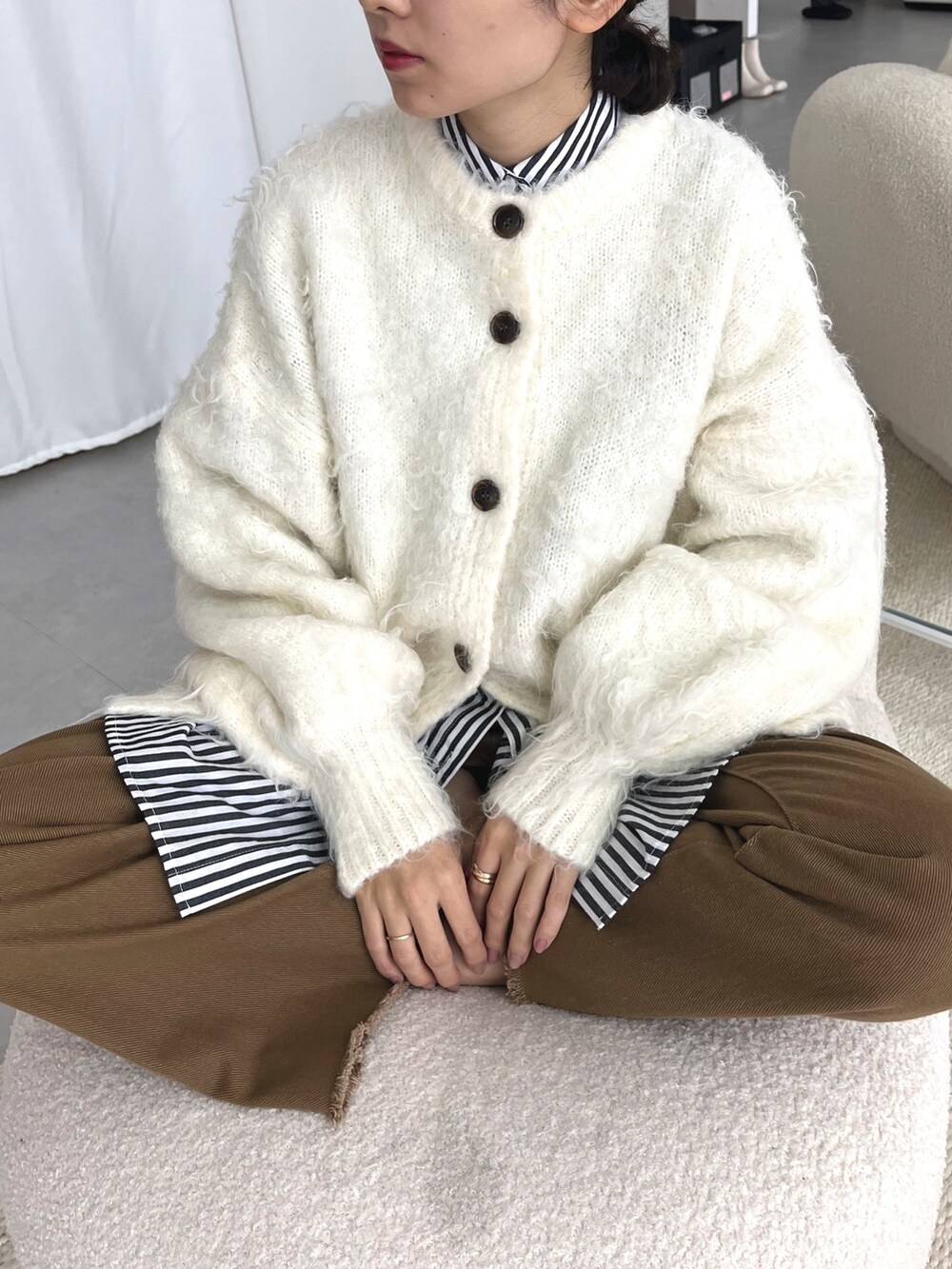 ホワイト系のカーディガン/ボレロ、ブルー系のシャツ/ブラウス、ブラウン系のデニムパンツを着用したレディースの冬コーディネートの2枚目の写真