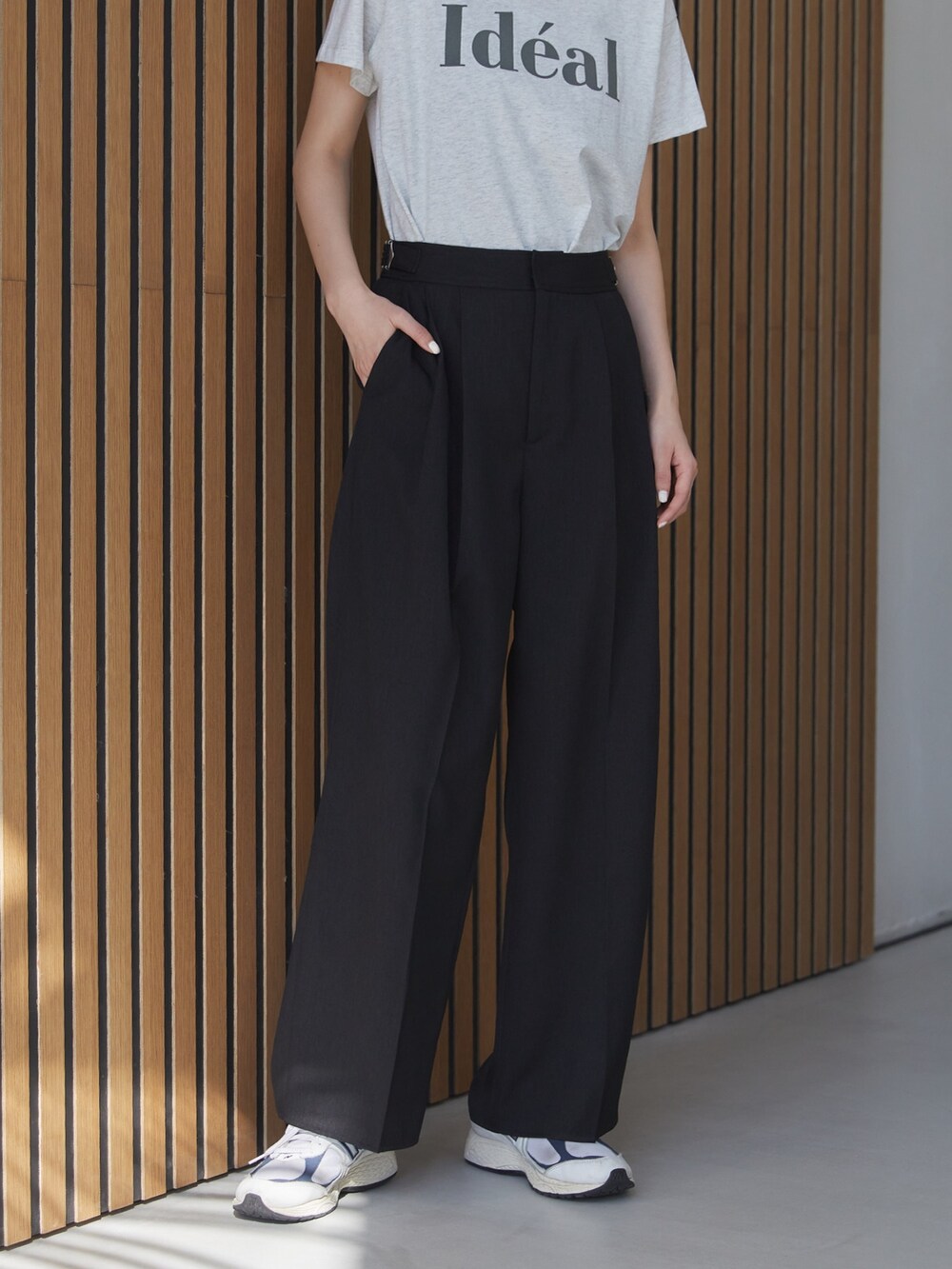 ブラック系のスラックス、ホワイト系のスニーカー、ベージュ系のTシャツ/カットソーを着用したレディースの夏コーディネートの4枚目の写真