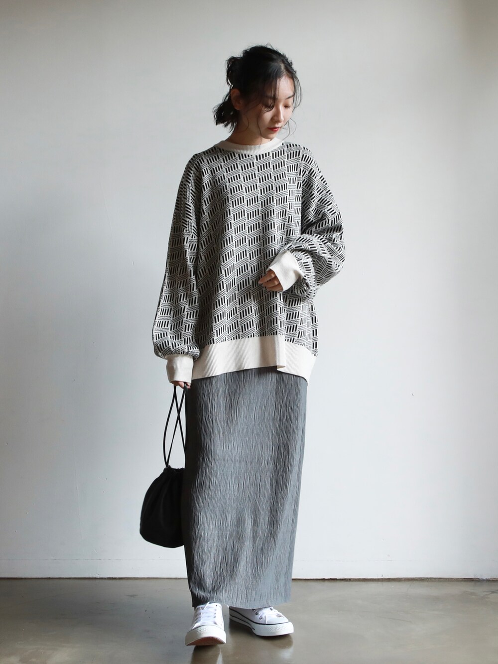 ブラック系のノーカラーコート、ブラック系のハンドバッグ、ホワイト系のスニーカーを着用したレディースの秋コーディネートの2枚目の写真