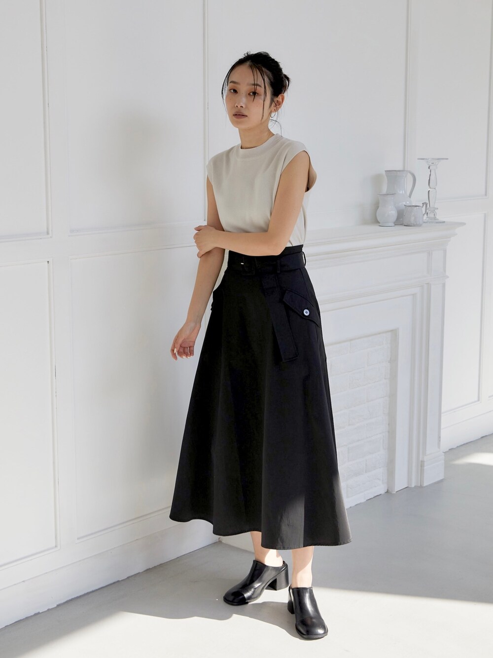 ブラック系のスカート、ホワイト系のニット/セーター、ブラック系のスリッポンを着用したレディースの夏コーディネートの3枚目の写真