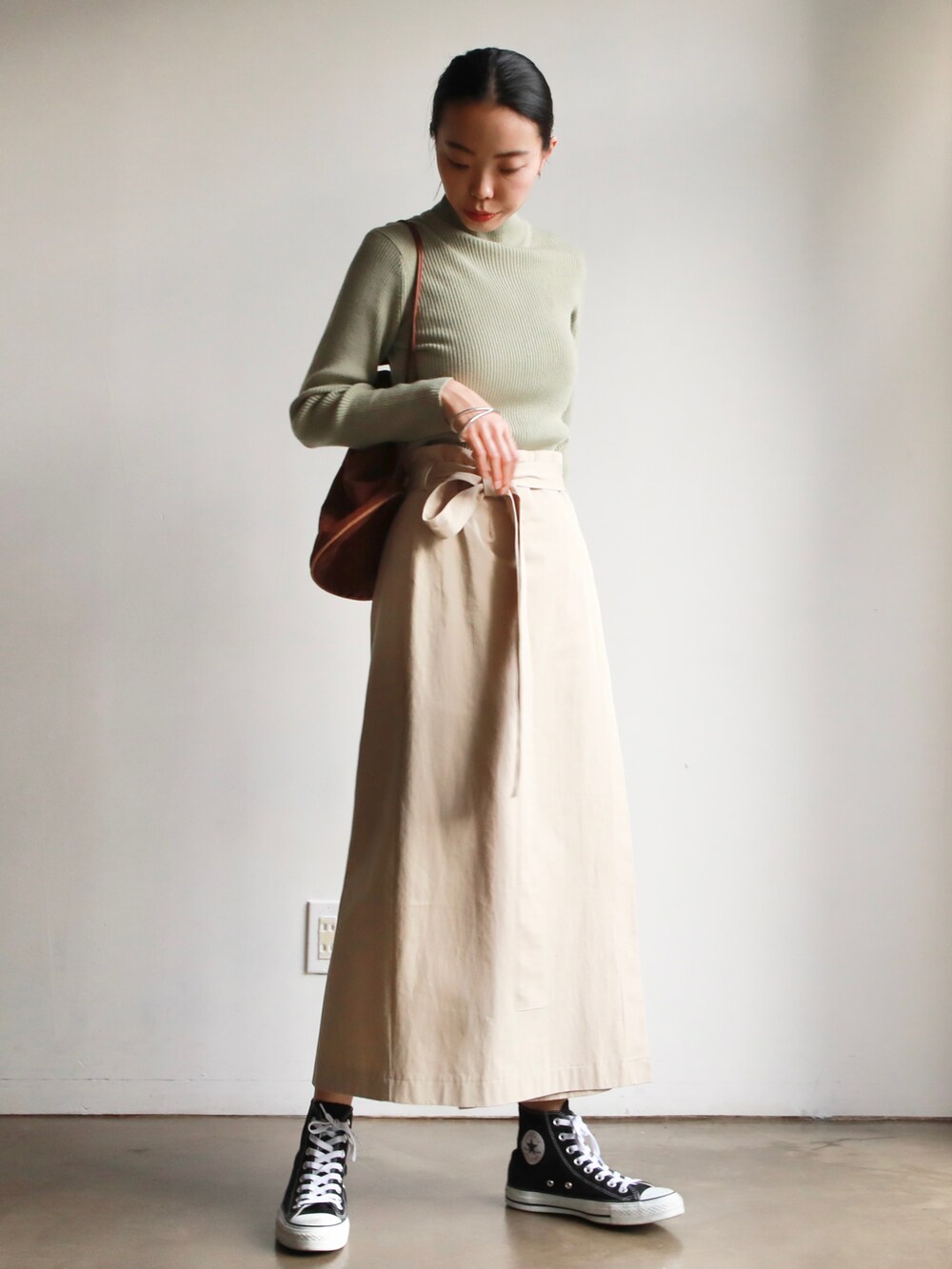 グリーン系のTシャツ/カットソー、ベージュ系のスカート、ブラック系のスニーカーを着用したレディースの冬コーディネートの3枚目の写真