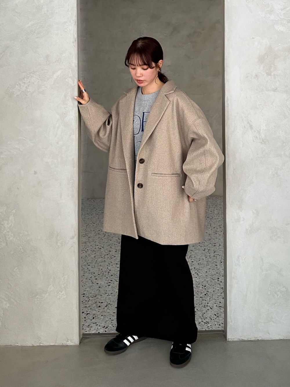 ブラック系のチェスターコート、グレー系のスウェット、ブラック系のスカートを着用したレディースの冬コーディネートの3枚目の写真