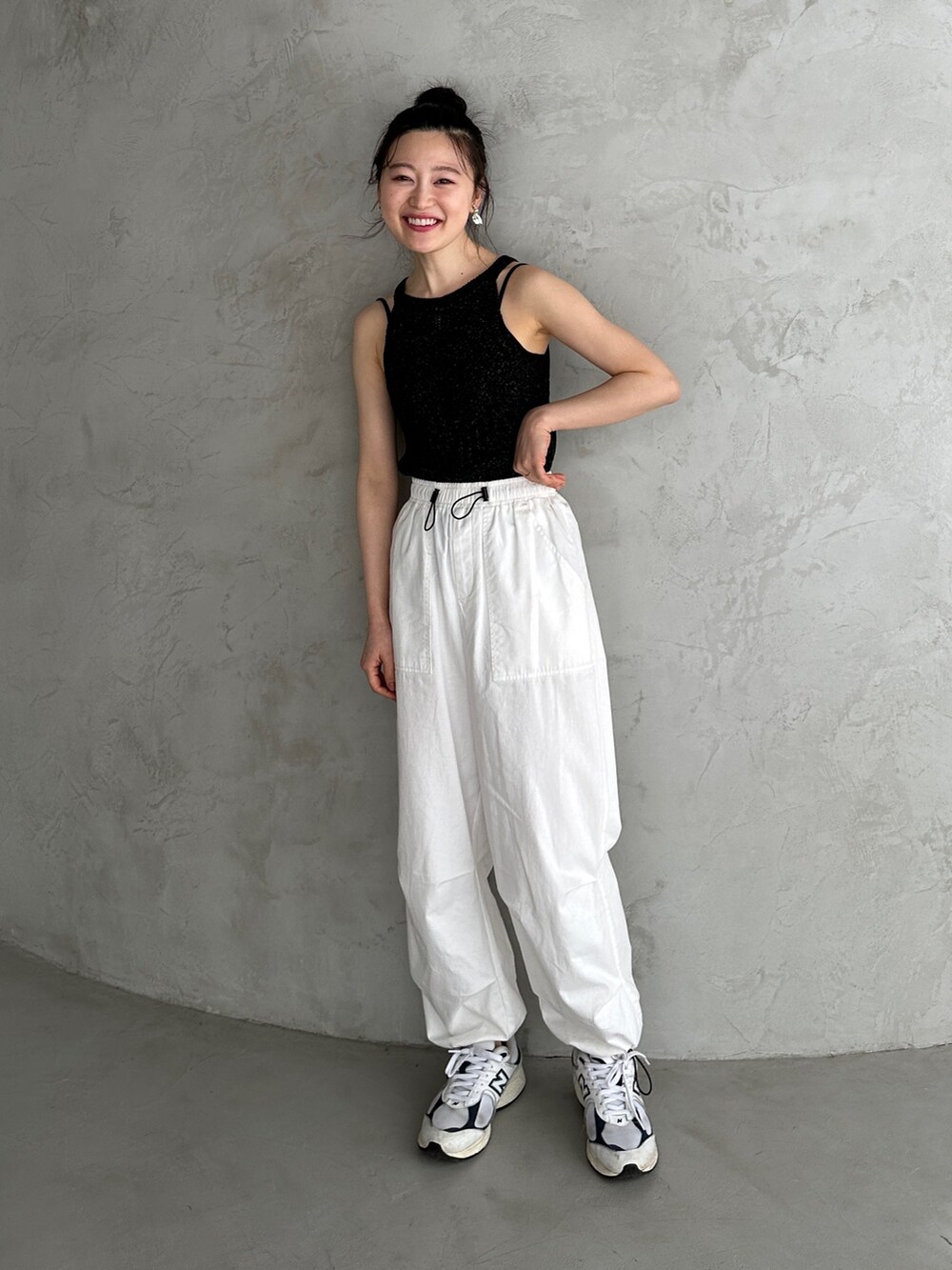 ブラック系のニット/セーター、ホワイト系のカーゴパンツ、ホワイト系のスニーカーを着用したレディースの春コーディネートの2枚目の写真