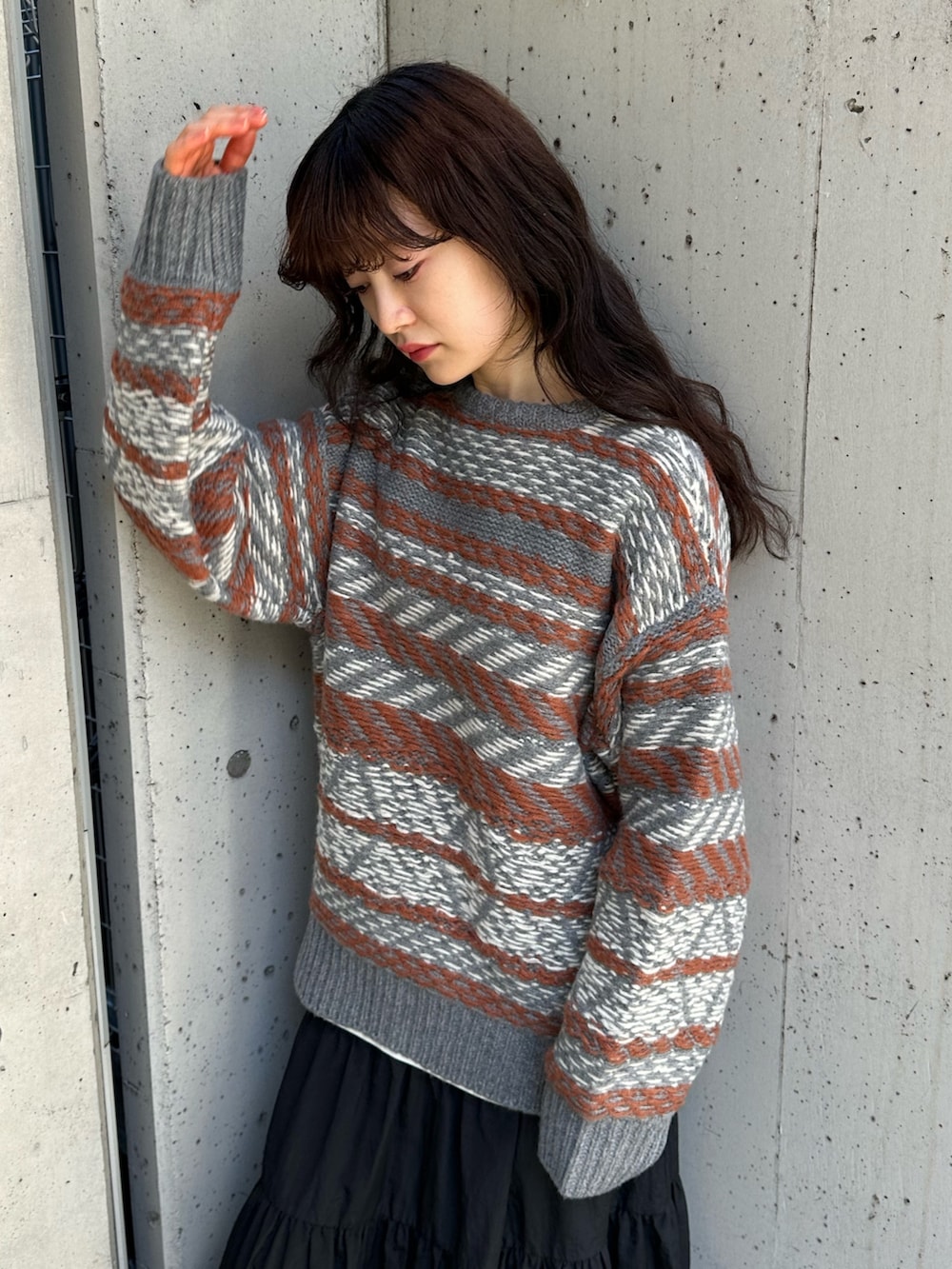 グレー系のニット/セーター、ブラック系のスカート、グレー系のスニーカーを着用したレディースの冬コーディネートの3枚目の写真