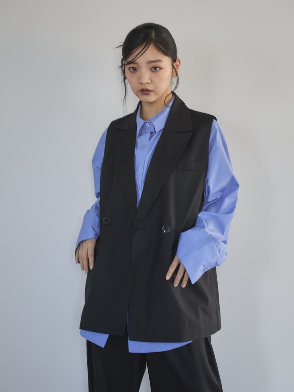 ブラック系のベスト、ブルー系のシャツ/ブラウス、ブラック系のスラックスを着用したレディースの冬コーディネートの3枚目の写真