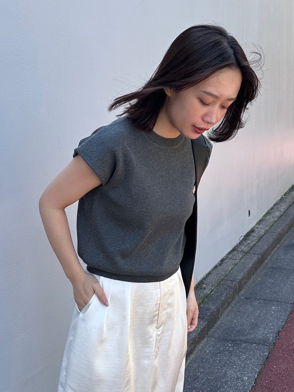 グレー系のニット/セーター、ブラック系のショルダーバッグ、ホワイト系のその他パンツを着用したレディースの春コーディネートの4枚目の写真