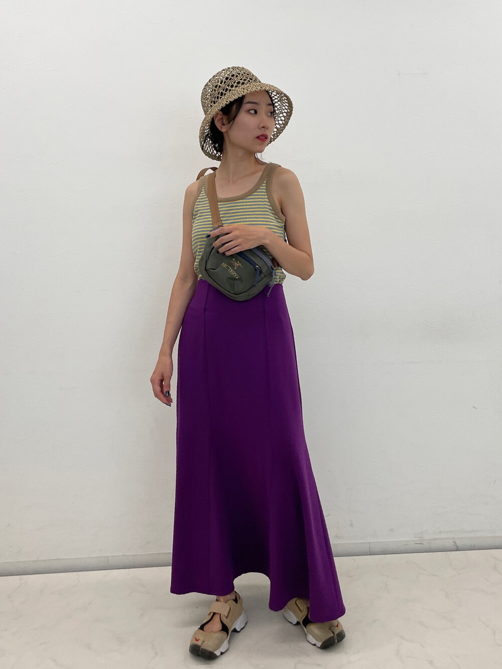 ブルー系のタンクトップ、グリーン系のショルダーバッグ、パープル系のスカートを着用したレディースの夏コーディネートの2枚目の写真
