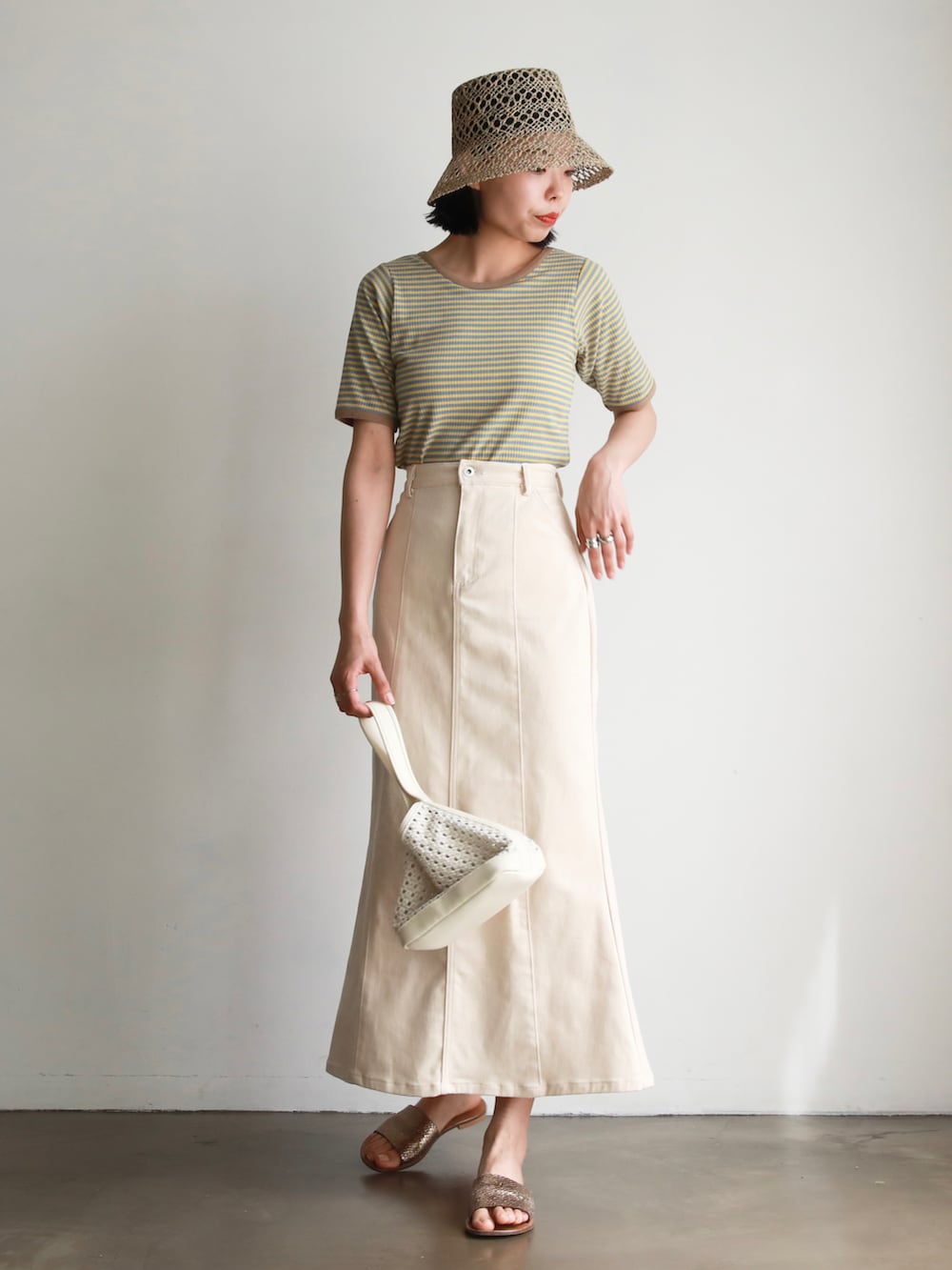 ブルー系のTシャツ/カットソー、ホワイト系のデニムスカート、ホワイト系のトートバッグを着用したレディースの春コーディネートの2枚目の写真