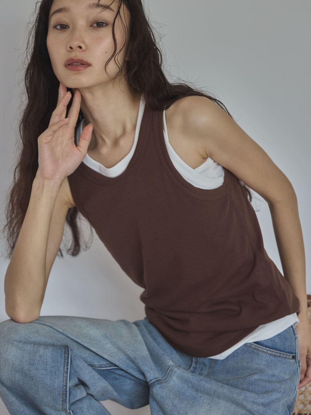 ホワイト系のタンクトップ、ブラウン系のタンクトップ、ブルー系のデニムパンツを着用したレディースの夏コーディネートの4枚目の写真