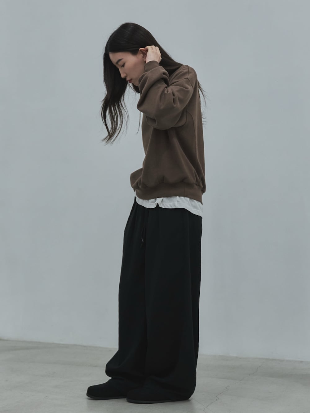 ブラック系のその他シューズ、ブラック系のスラックス、ホワイト系のTシャツ/カットソーを着用したレディースの秋コーディネートの2枚目の写真