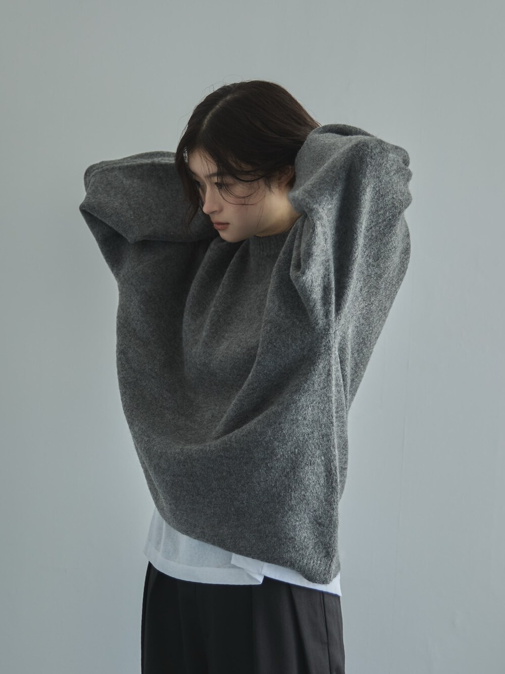 グレー系のニット/セーター、ホワイト系のTシャツ/カットソー、ブラック系のスラックスを着用したレディースの秋コーディネートの4枚目の写真