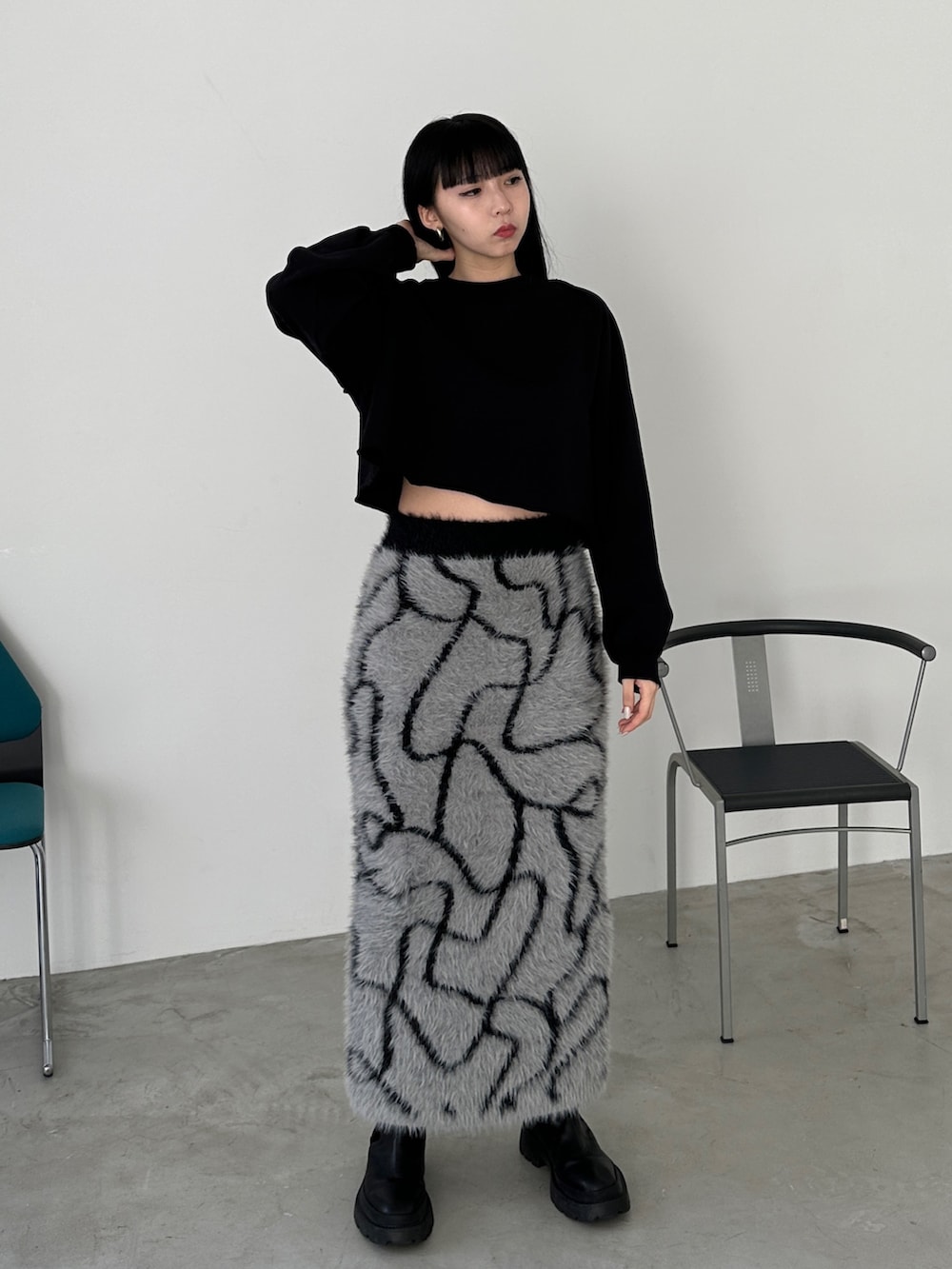 グレー系のスカート、ブラック系のブーツ、ブラック系のスウェットを着用したレディースの冬コーディネートの3枚目の写真