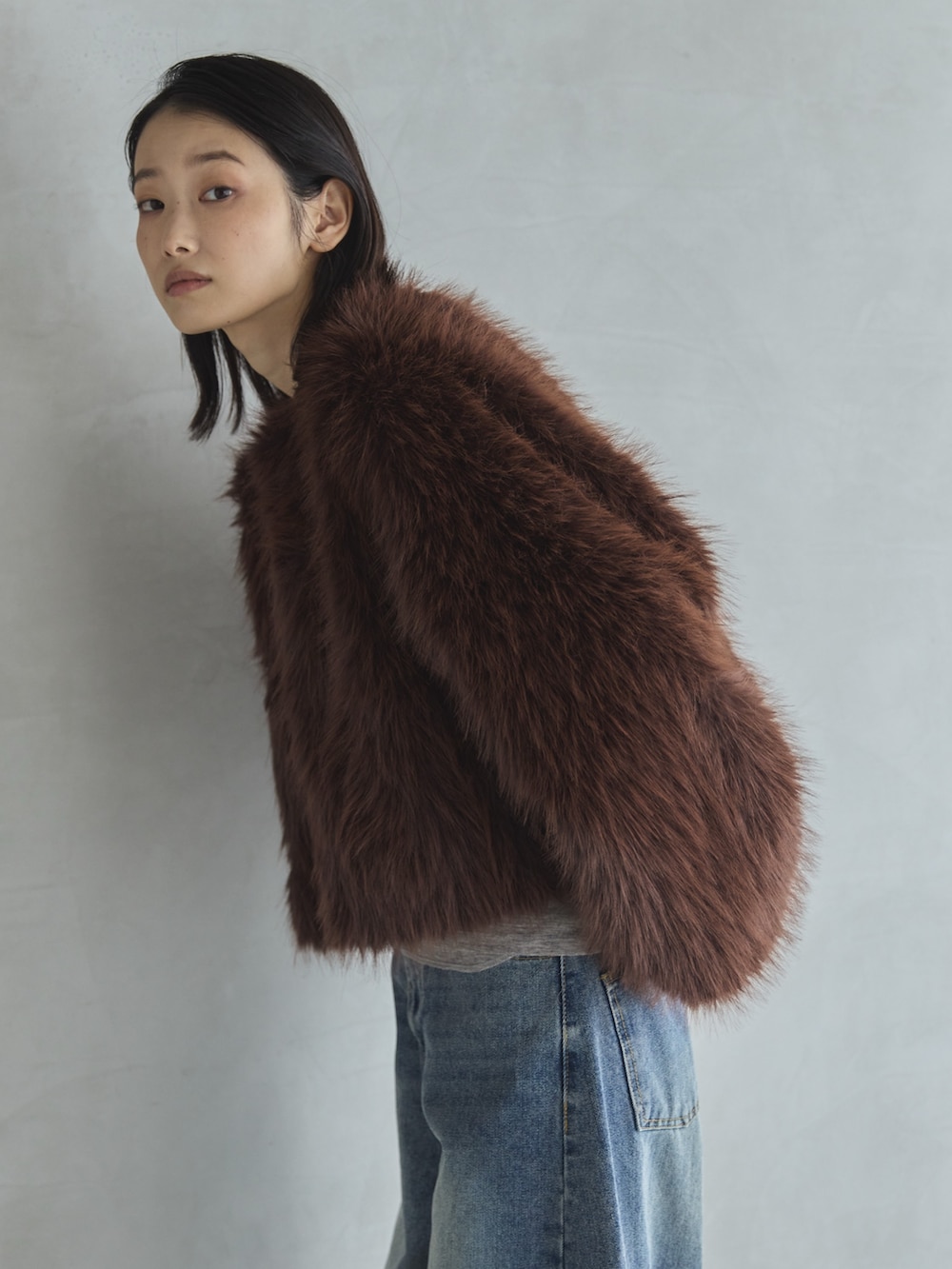 グレー系のTシャツ/カットソー、ブラウン系のその他アウター、ブルー系のデニムパンツを着用したレディースの冬コーディネートの2枚目の写真