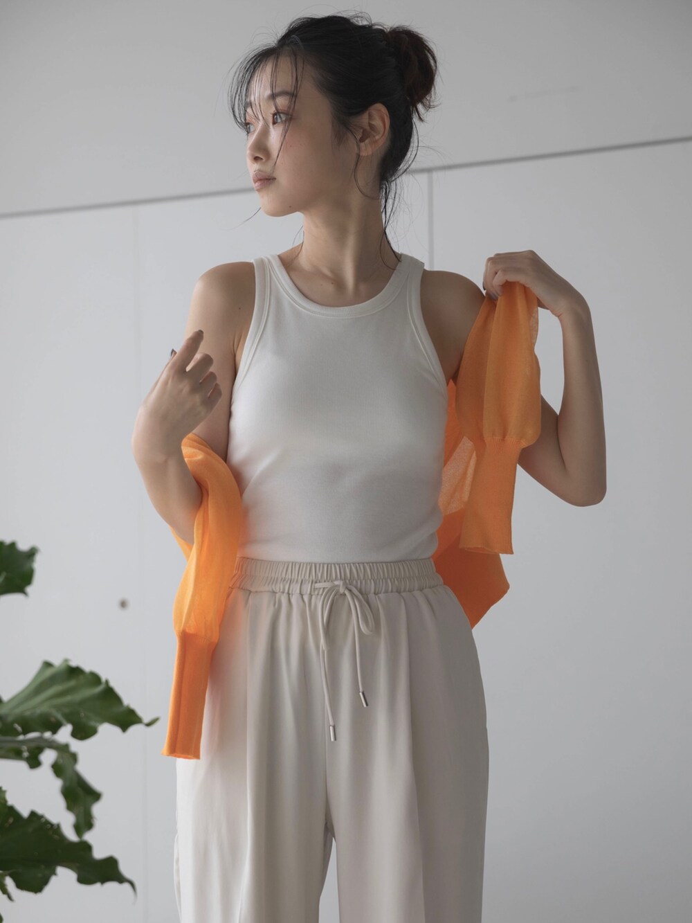ホワイト系のスラックス、オレンジ系のカーディガン/ボレロ、ホワイト系のタンクトップを着用したレディースの春コーディネートの4枚目の写真
