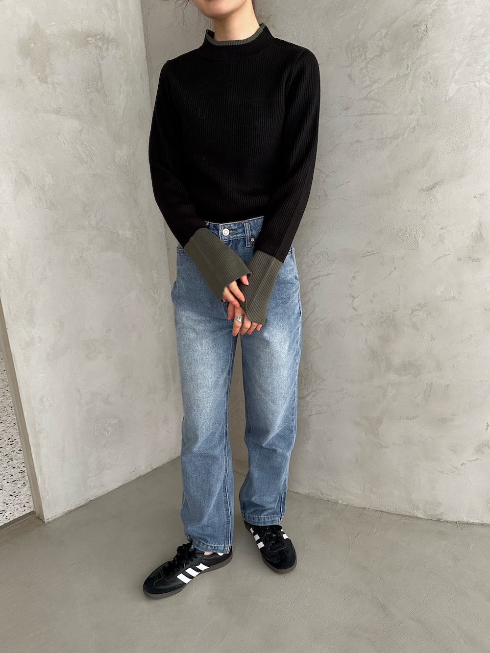 グレー系のニット/セーター、ブラック系のスニーカー、ブルー系のデニムパンツを着用したレディースの冬コーディネートの3枚目の写真