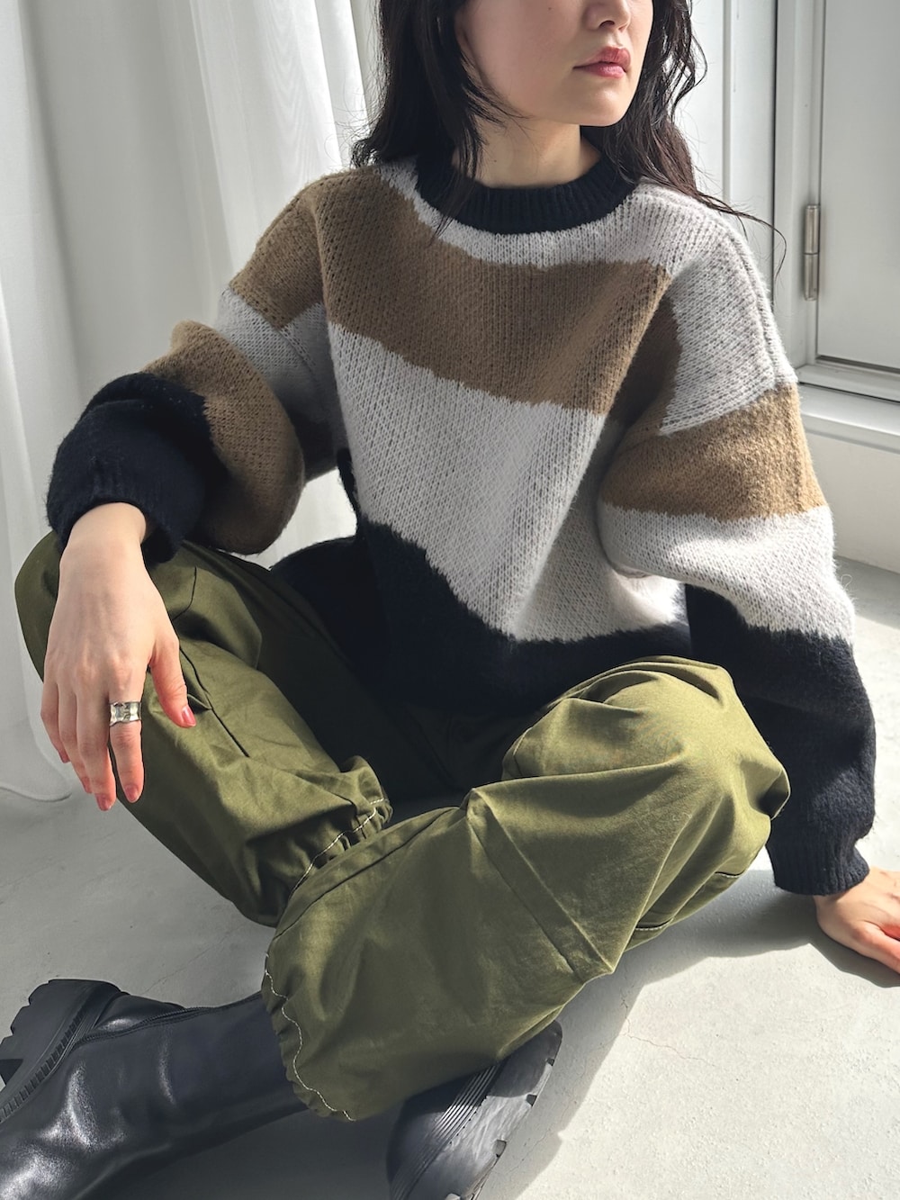 ベージュ系のニット/セーター、ホワイト系のスカート、ベージュ系のスニーカーを着用したレディースの秋コーディネートの3枚目の写真