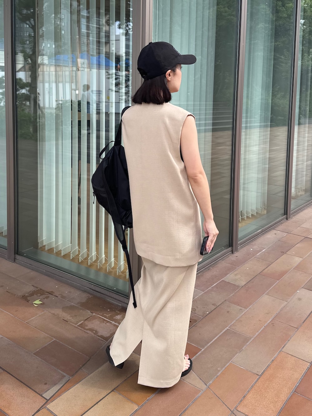 ホワイト系のベスト、ホワイト系のスカート、ブラック系のサンダルを着用したレディースの夏コーディネートの3枚目の写真