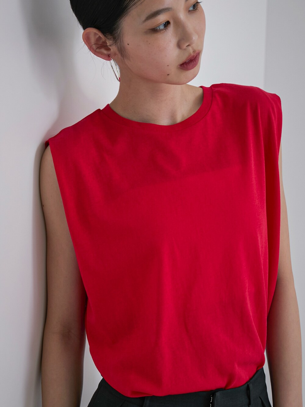 レッド系のタンクトップ、グレー系のスラックス、ブラック系のサンダルを着用したレディースの春コーディネートの3枚目の写真